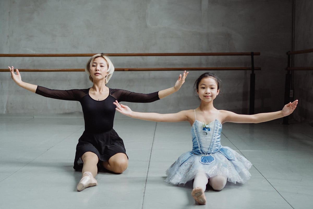 asian graceful girl doing ballet move with instructor